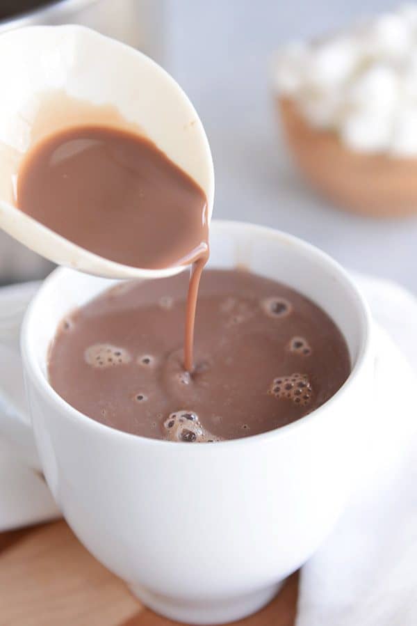 Se vierte una cucharada de chocolate caliente en una taza blanca. 