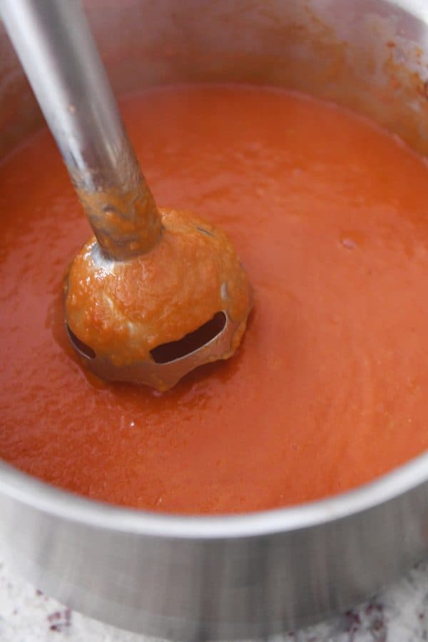 Revuelve la clásica sopa de tomate en la olla con una batidora de inmersión.