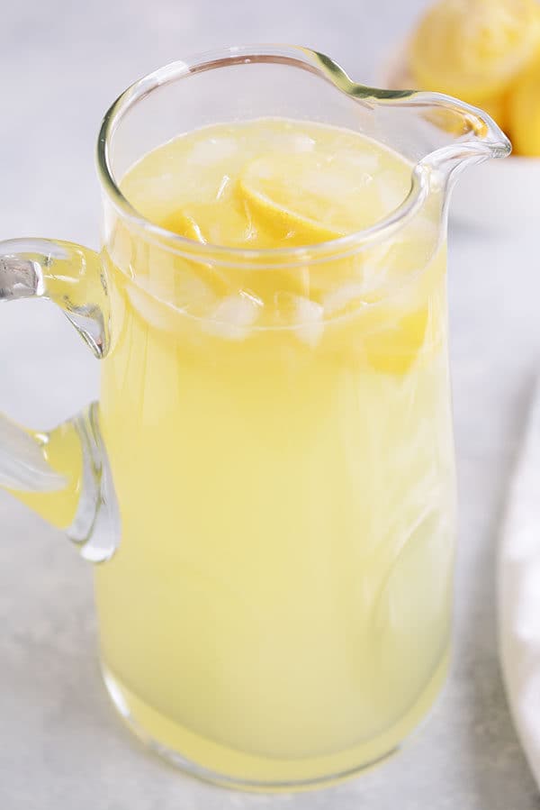 Un tarro de limonada fresca con cubitos de hielo y rodajas de limón. 