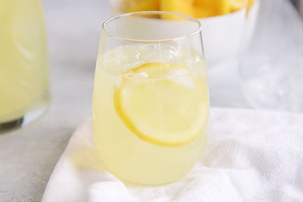 Un vaso de limonada con hielo y una rodaja de limón.