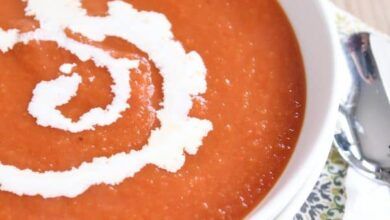 La mejor sopa de tomate clásica en un bol blanco con un remolino de crema espesa