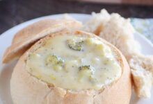 Sopa de queso brócoli casera en un tazón de pan en la placa blanca.