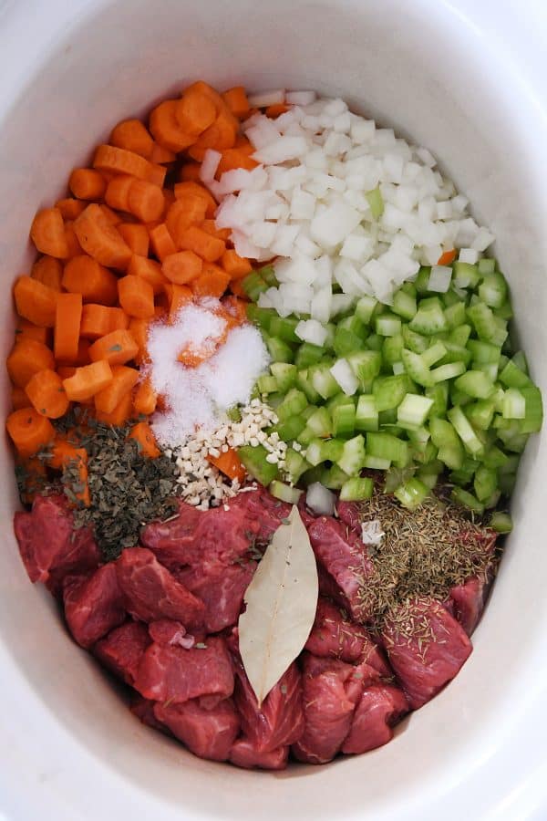 Vista desde arriba de carne de res, verduras y condimentos en una olla de cocción lenta
