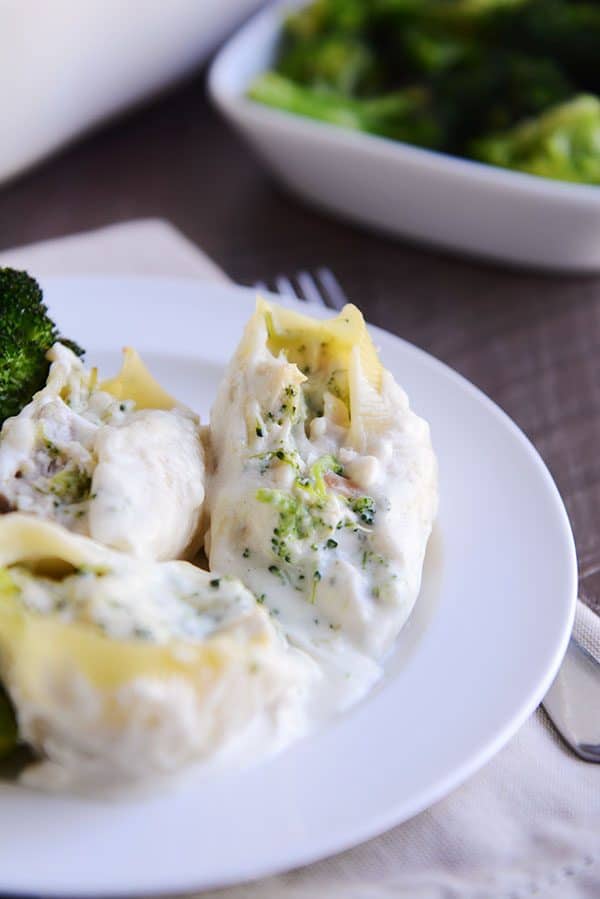 En el plato blanco había tres conchas de pasta rellenas de brócoli y Alfredo. 