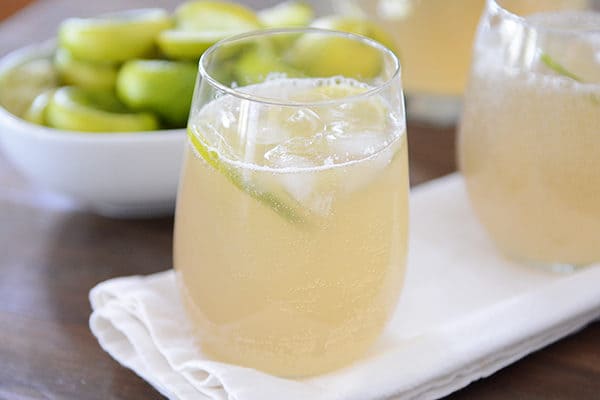 Ponga dos vasos de limonada helada frente a un tazón de rodajas de limón. 