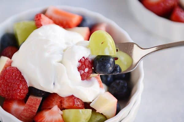 Tome un bocado de la ensalada de frutas de yogur de los moldes blancos con un tenedor.