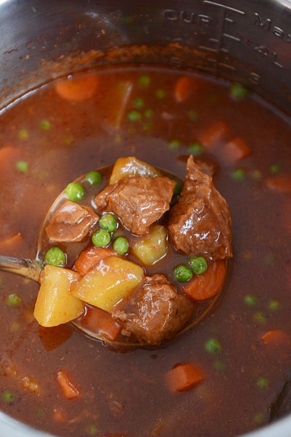 En una olla instantánea llena de guiso, use una cuchara para sacar una cucharada de carne, papas, zanahorias, guisantes y guiso. 