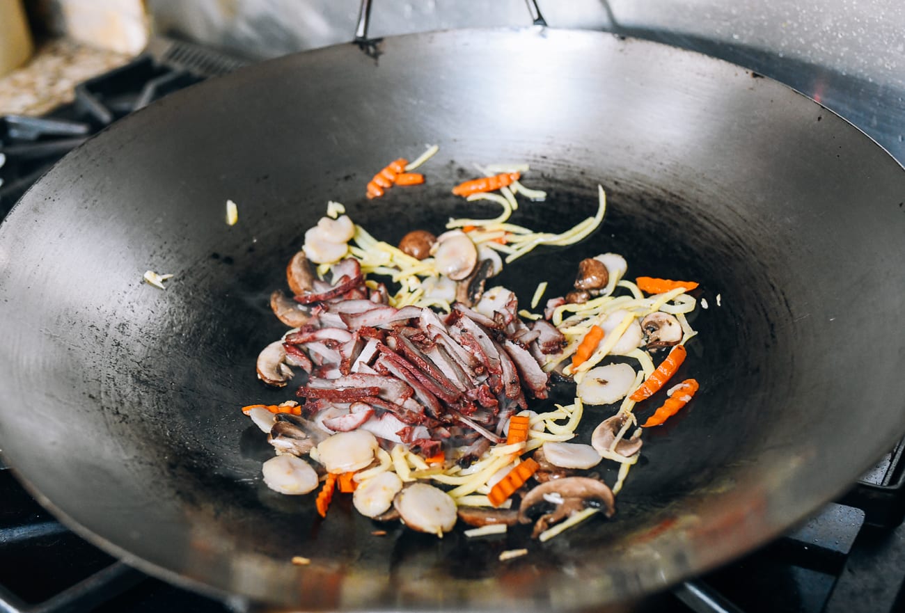 Agregue cerdo asado chino desmenuzado a las verduras en el wok