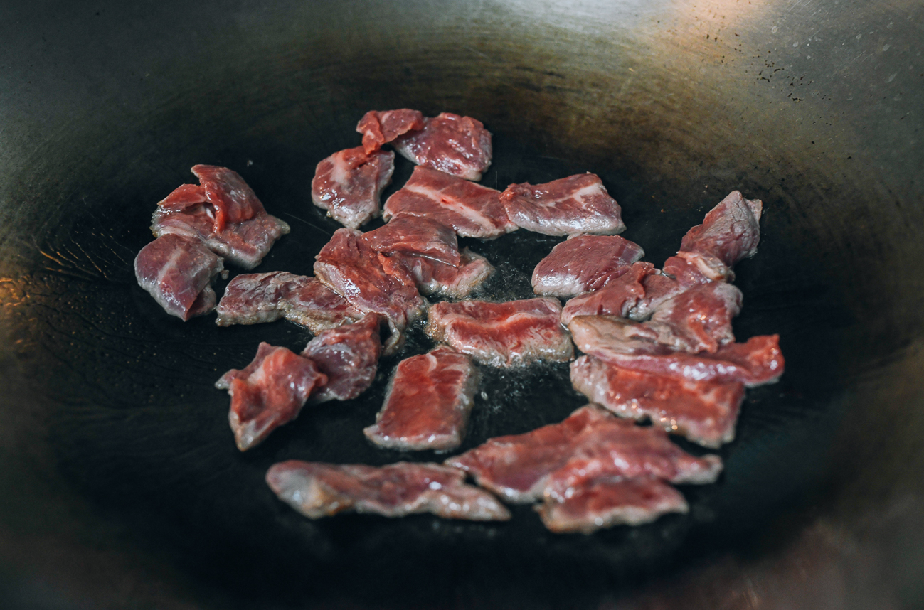 Agrega la carne cortada en una sola capa al wok.