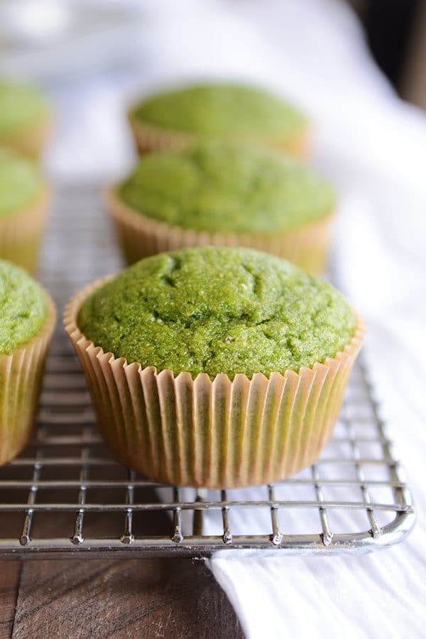 Muffins verdes con forro marrón para muffins en una rejilla para enfriar