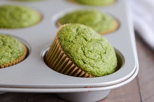 Hornee muffins verdes en un molde para muffins, y uno de los muffins se vierte de una cubeta.
