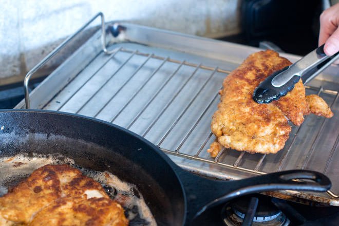 Use pinzas para mover las chuletas de pollo a la rejilla de la bandeja para hornear.