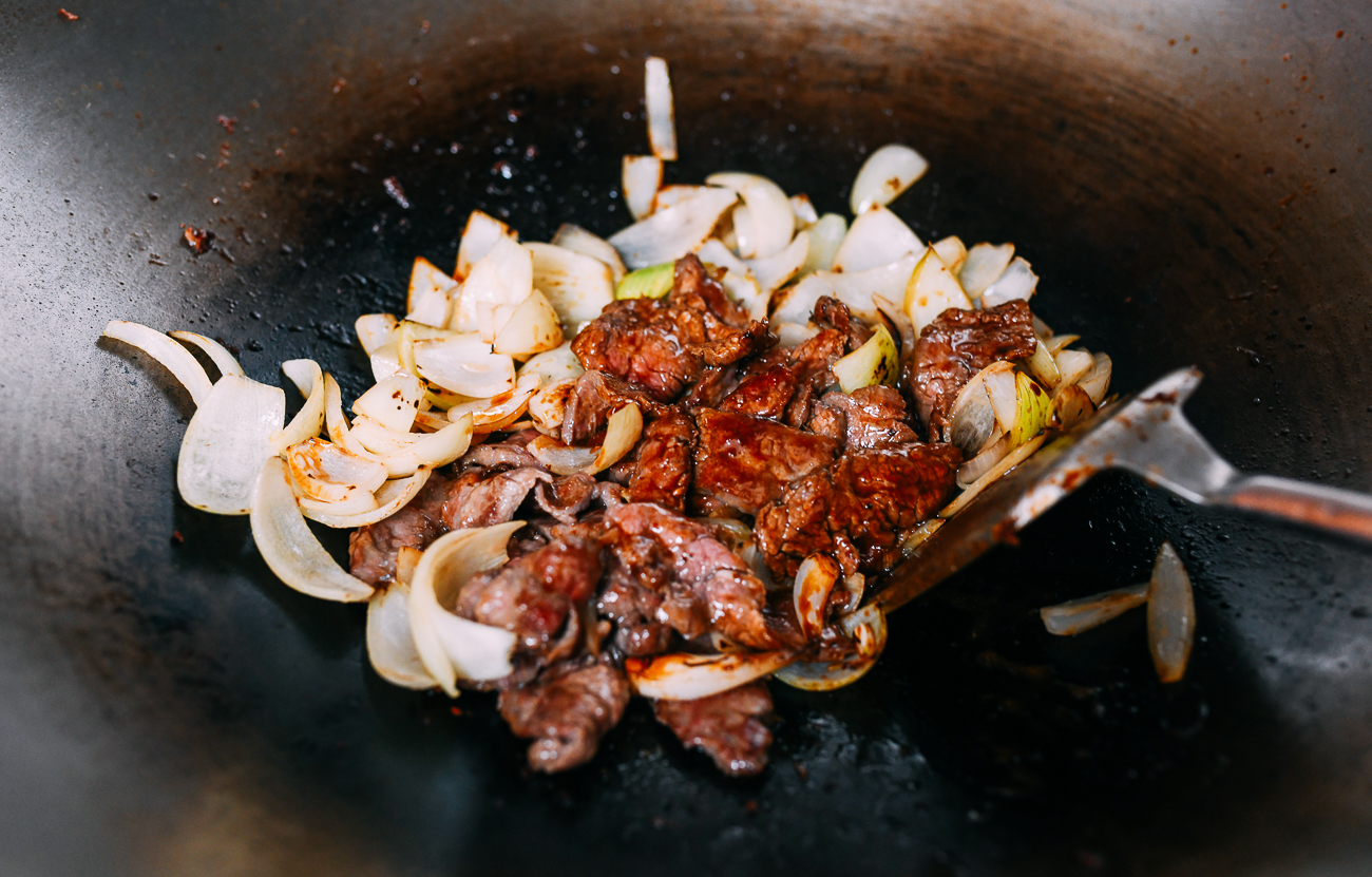 Revuelva la carne y la cebolla en un wok en una salsa.