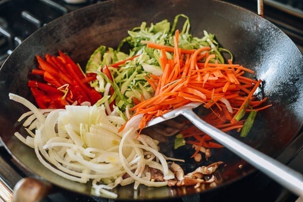 Agregue repollo, zanahorias, cebollas y pimientos a un wok, thewoksoff.com