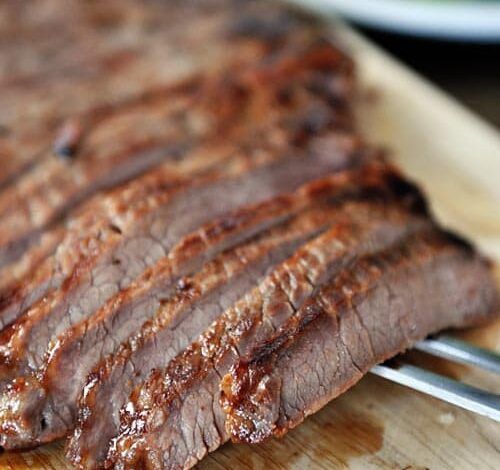 Bistec a la parrilla cortado en tiras en una tabla para cortar.
