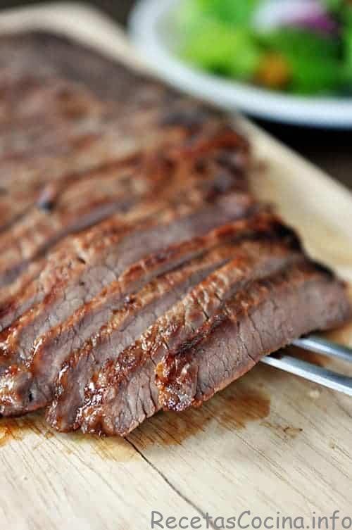 Bistec a la parrilla cortado en tiras en una tabla para cortar.