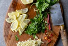 Tabla de cortar con ajo, rodajas de limón, cilantro y ají