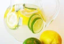 Jarra de cristal con ponche transparente y rodajas de limón y lima