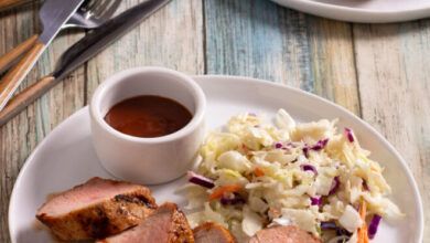 Coloque las rebanadas de lomo de cerdo BBQ en un plato blanco con ensalada de col y salsa BBQ.