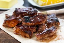 Country style pork ribs with BBQ sauce on a white platter.