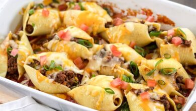 Taco Stuffed Shells topped with cheese, green onion, and tomato.