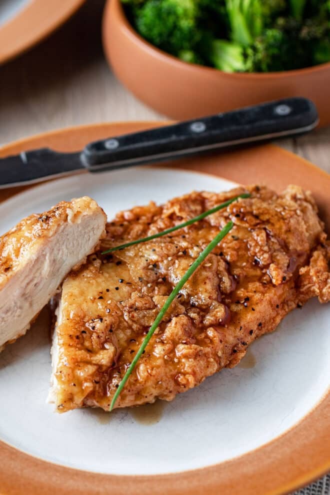 Pollo crujiente con ajo y miel en un plato con una rebanada cortada.