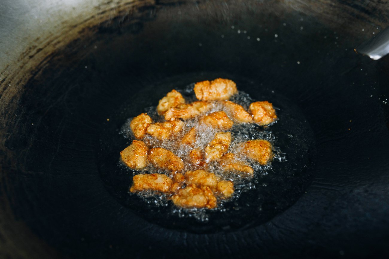 freír trozos de pollo poco profundos en un wok grande