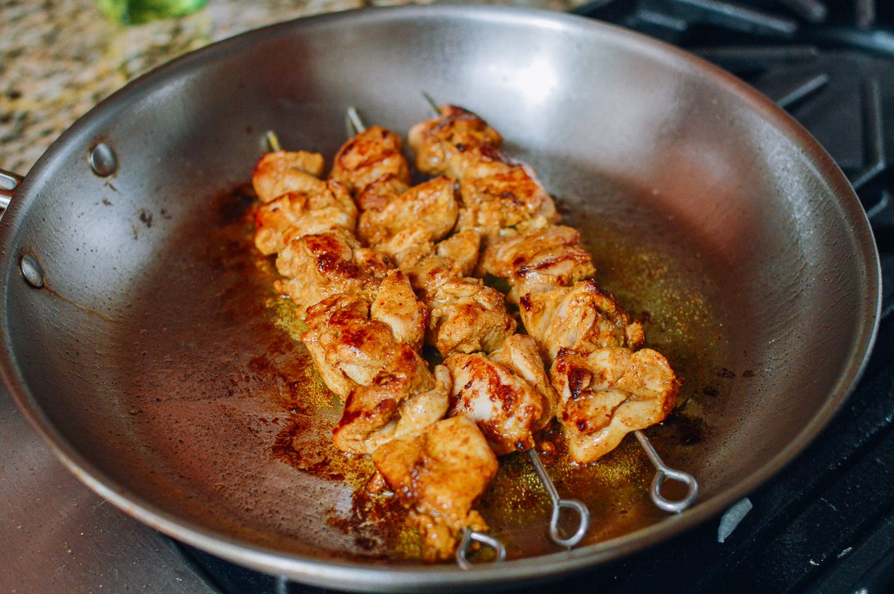 cocinar brochetas de pollo satay en una sartén en la estufa