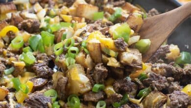 Ground Beef and Potatoes in skillet topped with cheese and green onion.